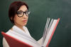 Teacher holding a book in front of the chalkboard Teacher holding a book in front of the chalkboard