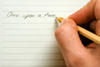 Person writing "Once upon a time" with a pencil on lined paper Person writing "Once upon a time" with a pencil on lined paper