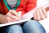 someone holding book in lap and writing someone holding book in lap and writing